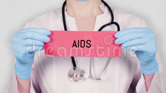 特写双手戴蓝色医用手套手持撕红纸卡上刻有艾滋病字样穿白衣服的医生视频的预览图