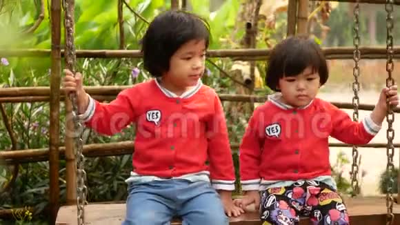 两个亚洲小女孩姐妹喜欢一起骑秋千姐妹关系友谊视频的预览图