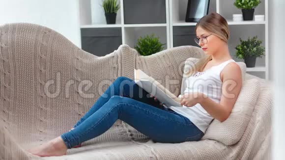 自信的学生年轻女孩专注阅读课本翻页躺在沙发上享受学习视频的预览图
