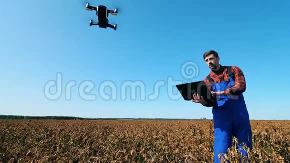 农业工人用笔记本电脑控制无人机同时站在田野上视频的预览图