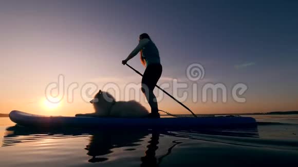 一个年轻女子和她的狗的站立划桨视频的预览图