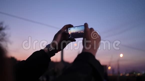男人手拿着手表为夜城的日落拍照视频的预览图