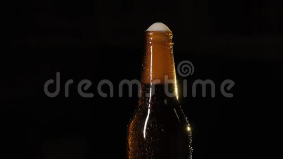 一瓶啤酒被一只雄性的手打开一瓶啤酒在黑色背景特写上滴着水视频的预览图
