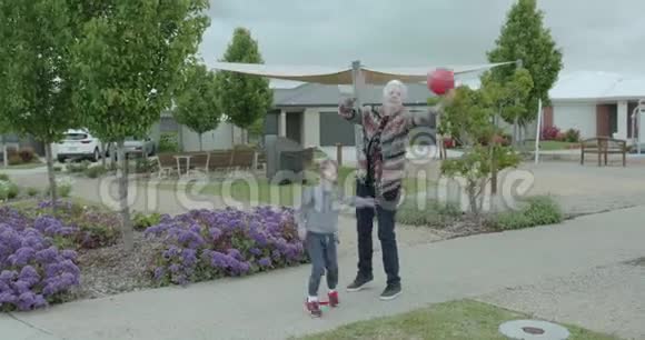 年长的女人和一个年轻的男孩打篮球那个女人把球扔给他他把球拍回来视频的预览图