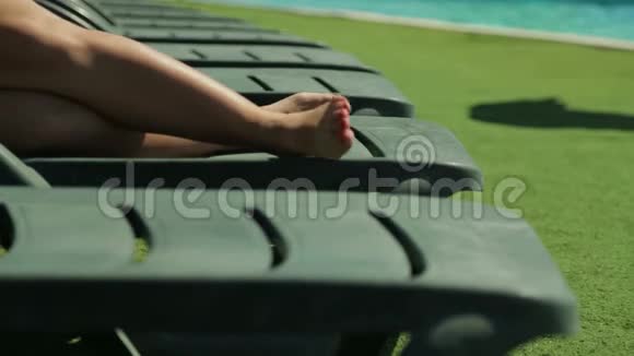 女腿在泳池边的躺椅上视频的预览图