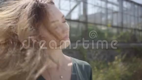 一幅可爱的年轻女人在阳光下的温室背景上摇着头长出了头发健康视频的预览图
