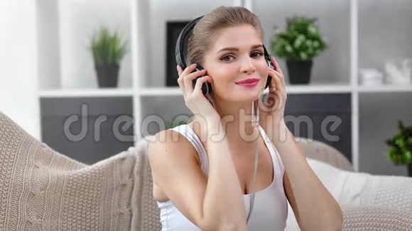可爱积极的欧洲女孩戴着耳机享受着美妙的旋律在家玩得很开心视频的预览图