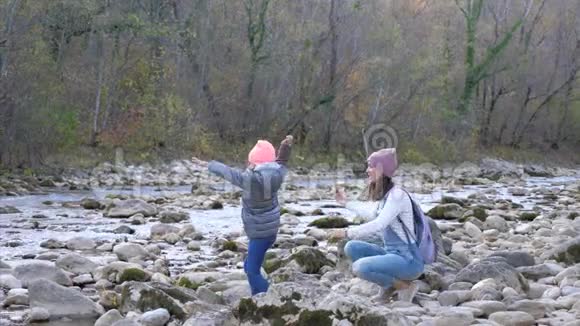 年轻的母亲和小女儿正在把石头扔进山河视频的预览图
