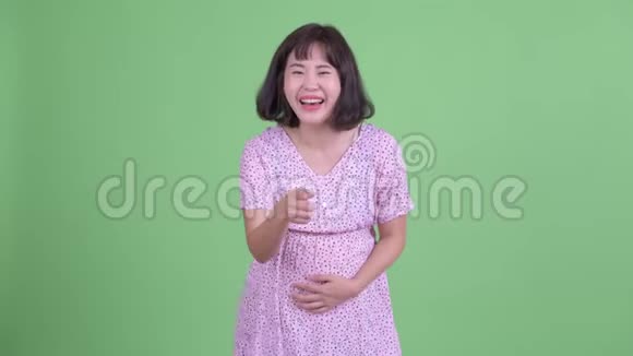 快乐的亚洲孕妇笑着指着镜头视频的预览图