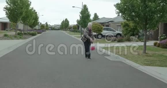 一位老太太和一个小女孩在街上打篮球小女孩把球扔给那个女人她接住了球视频的预览图