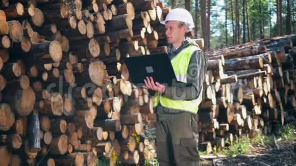 砍伐树木和一名男性工人在附近操作笔记本电脑视频的预览图