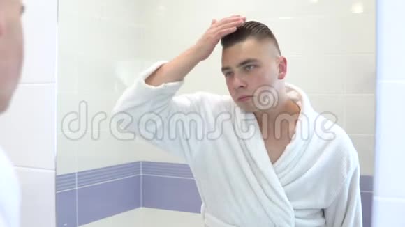 一个年轻人在镜子里崇拜自己一个穿着白大褂的人把头发伸直手指对着镜子视频的预览图