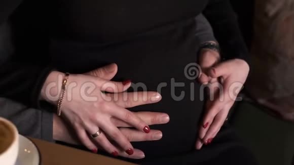 男女双手抚摸孕妇的腹部家庭幸福坐在咖啡馆里视频的预览图