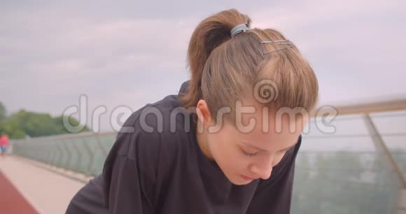 穿着黑色t恤的年轻活泼的女性慢跑者的特写镜头变得很有动力开始在上面奔跑视频的预览图