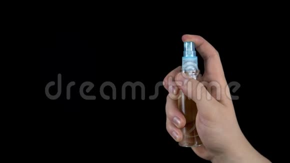 女人在黑色背景上洒香水一瓶香水在手特写视频的预览图
