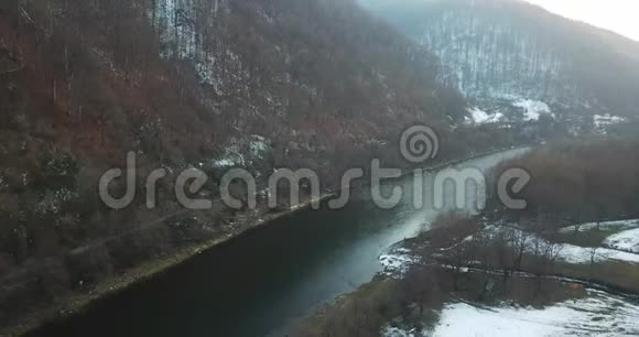 一架无人机沿着雪岸上的一条冬天的河流飞行视频的预览图