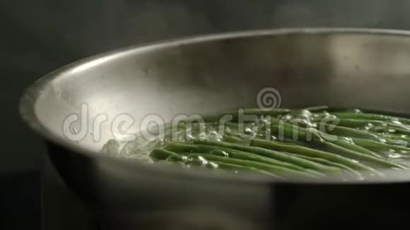 厨房金属锅中的绿色豆子沸腾视频的预览图
