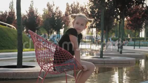 坐在水上金属椅子上的少女坐在饮水机前的椅子上的女孩感到非常放松视频的预览图