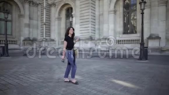一个年轻漂亮的女人黑发穿着牛仔裤和黑色T恤穿过巴黎实时宽镜头视频的预览图