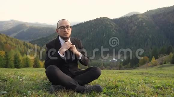 一个穿现代办公服的人盘腿坐在山上视频的预览图