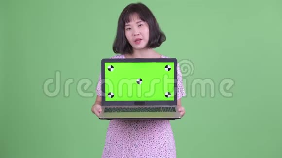 快乐的亚洲孕妇一边说话一边展示笔记本电脑视频的预览图