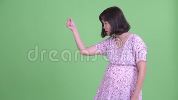快乐的亚洲孕妇拍打手指展示一些东西视频的预览图
