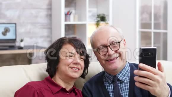 快乐的老夫妇坐在沙发上自拍视频的预览图
