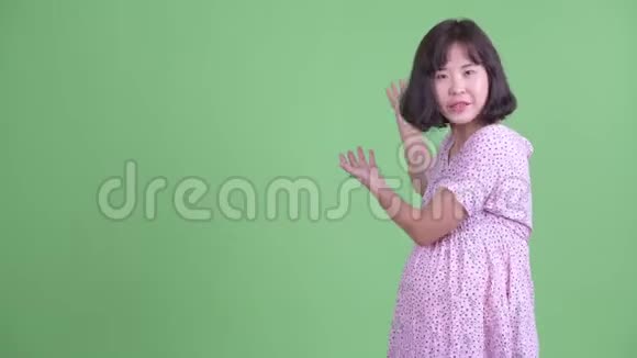 快乐的亚洲孕妇一边说一边向后看视频的预览图