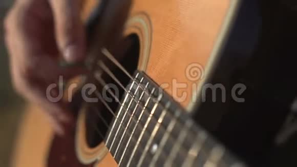 男子演奏和调声吉他特写镜头侧面拍摄室外视频的预览图