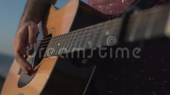 男子演奏和调声吉他特写镜头侧面拍摄室外视频的预览图