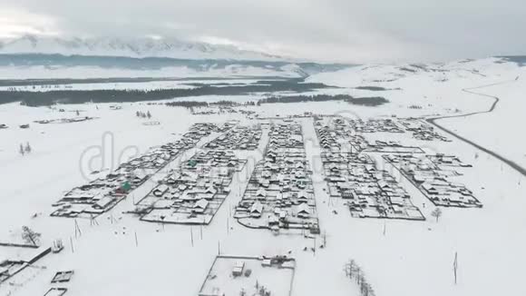空中观景阿尔泰冬天飞越白雪覆盖的西伯利亚村庄空中景观视频的预览图
