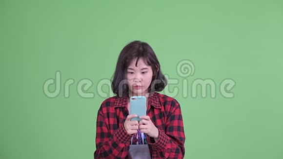 一脸快乐的亚洲时髦女人用电话和看起来惊讶视频的预览图