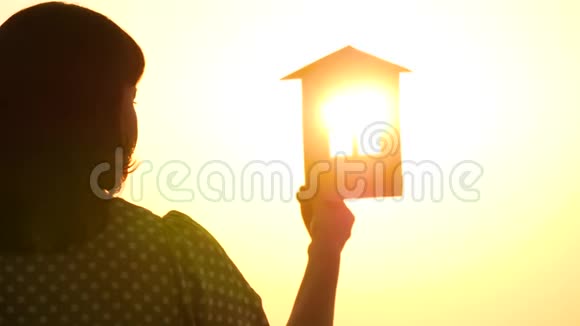 日落时一个女孩的剪影里面有房子特写的模型太阳光线穿过窗户视频的预览图