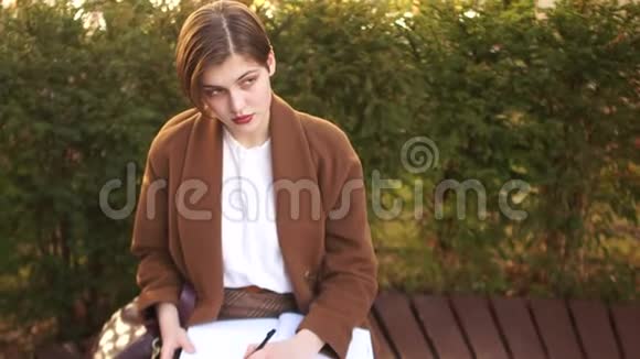 学生坐在公园的长凳上准备考试留着笔记本和摘要的短发女孩视频的预览图