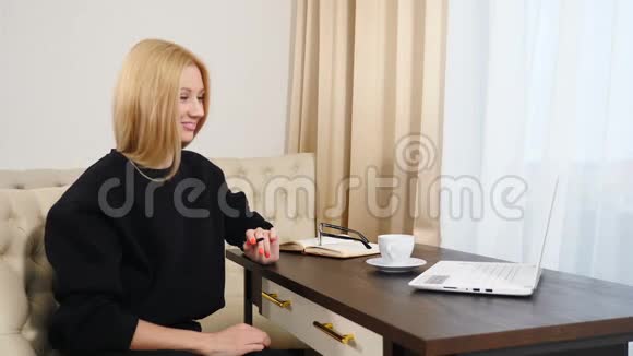 漂亮的年轻商务女性穿着黑色衣服坐在酒店房间里用左手在记事本上写笔记视频的预览图
