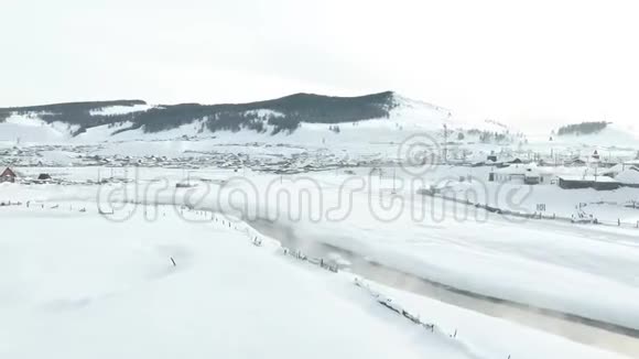 空中观景阿尔泰冬天飞越白雪覆盖的西伯利亚村庄空中景观视频的预览图