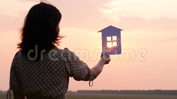 抱着纸房子的女孩太阳光线穿过纸房的窗户视频的预览图