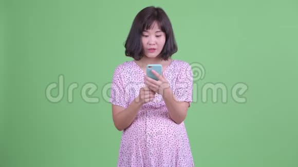快乐的亚洲孕妇用电话得到好消息视频的预览图