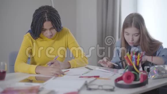 聪明的女学生坐着笔记本说话的肖像非裔美国人和高加索女孩视频的预览图
