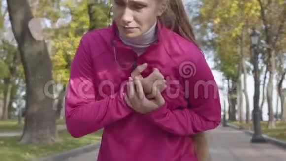 一位穿着粉色运动服胸部疼痛的白人美女的特写女生跑步时感觉不好视频的预览图