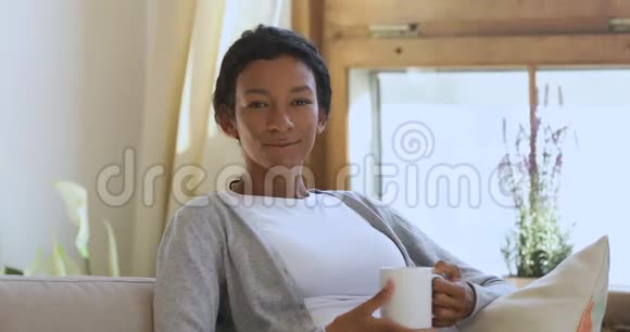 快乐的非洲女人在家喝咖啡放松的肖像视频的预览图