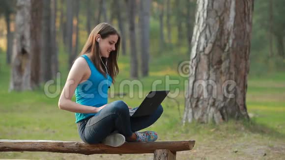 大自然中使用笔记本电脑说话和工作的年轻美女视频的预览图