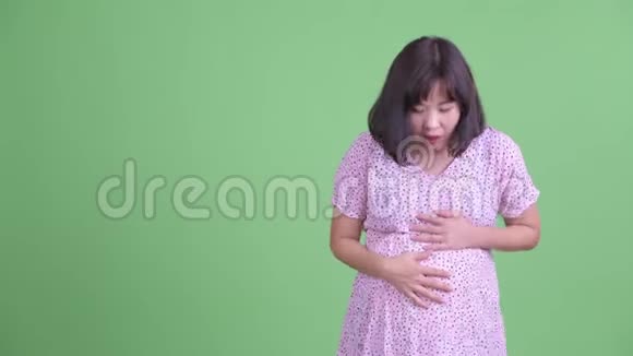 快乐的亚洲孕妇展示了一些东西看上去很惊讶视频的预览图
