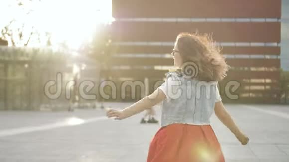 快乐的女人听音乐在户外用耳机跳舞穿休闲服装留着卷发的女孩子视频的预览图