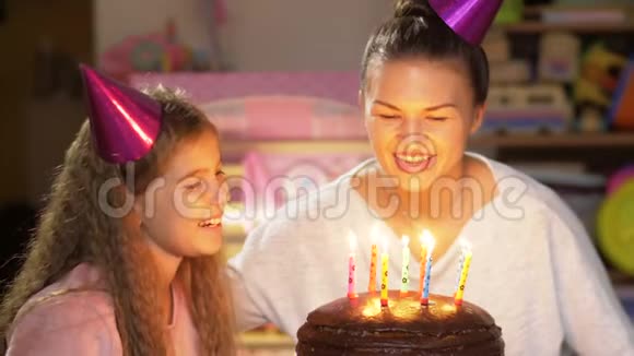 母亲和女儿在聚会上吹灭生日蛋糕上的蜡烛许愿视频的预览图