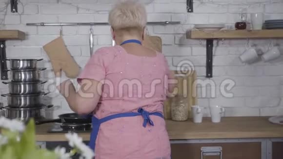 在厨房做饭的时候一位年长的金发白种人女人拿着一束黄色郁金香成熟的丈夫视频的预览图