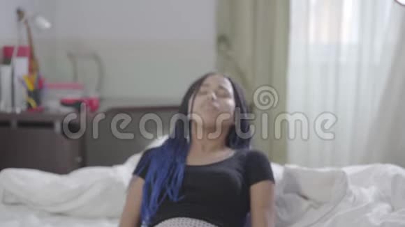 年轻的非裔美国女孩坐在床上修理可怕的东西然后离开一幅美丽的女人醒来视频的预览图