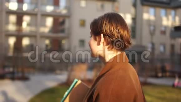 秋天阳光明媚的一幅短发少女画像幸福的女人手里拿着一个文件夹背景是多个视频的预览图
