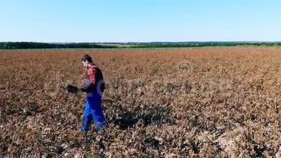 带笔记本电脑的农业工人在田里散步检查庄稼视频的预览图