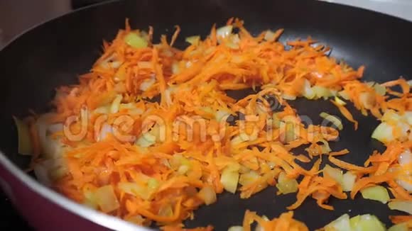 在煎锅上煎胡萝卜煎锅里的蔬菜橙色胡萝卜靠近视频的预览图